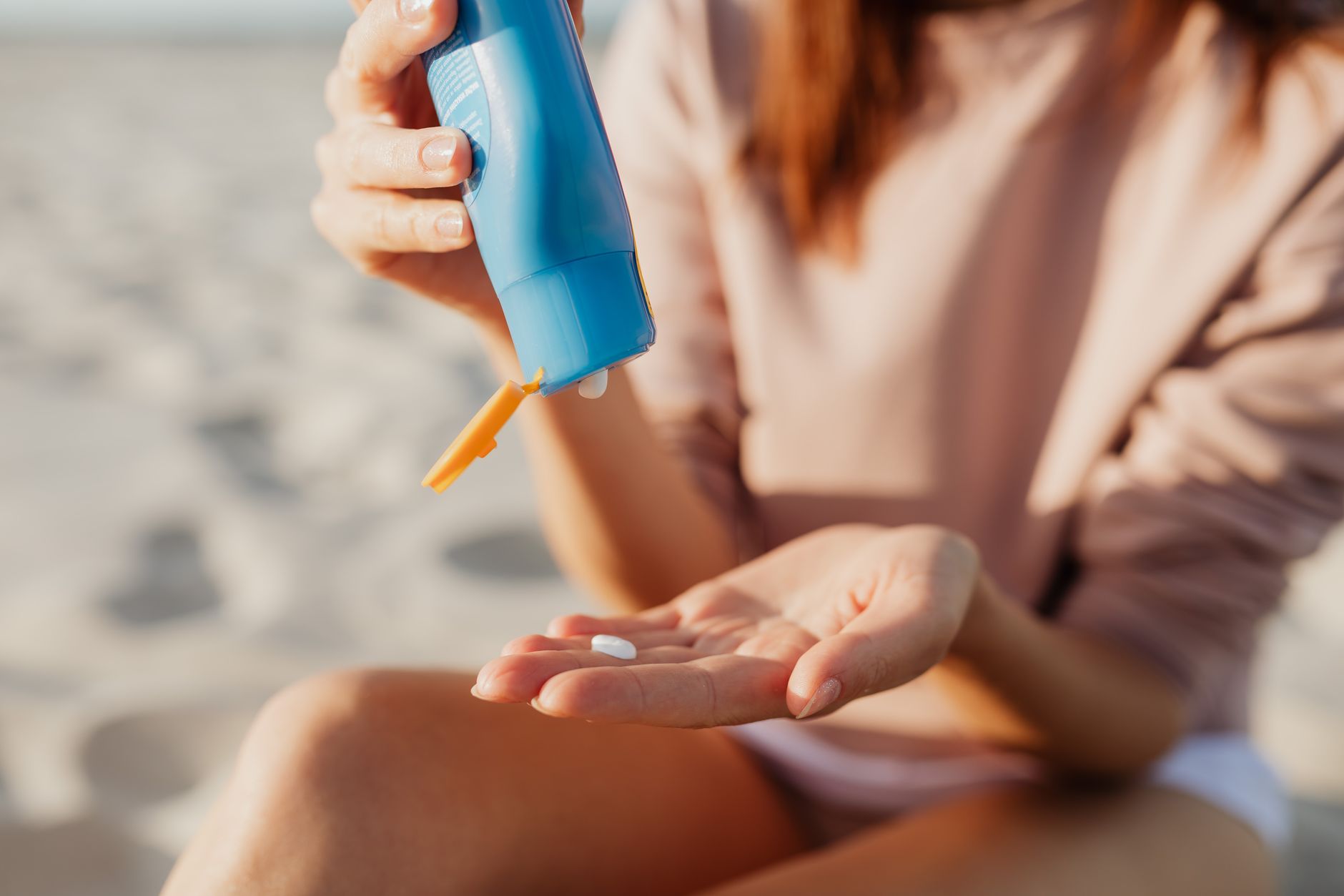 Rows of sunscreen bottles lined up on a beach towel near the shoreline